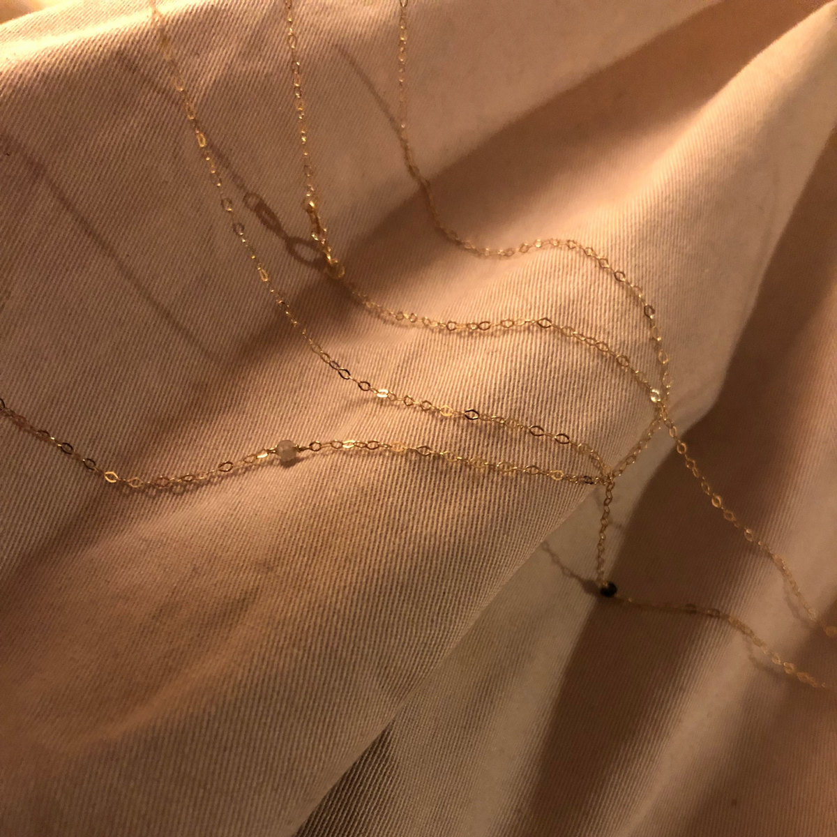 Set MandalaT composto da collana e braccialetto in oro sottile con piccoli diamanti naturali su tessuto beige