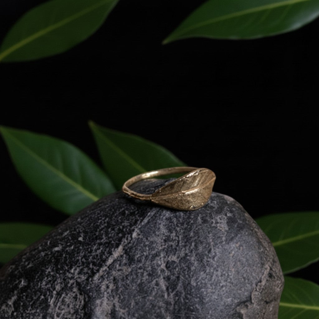 Anello Alloro MandalaT in metallo dorato con design a forma di foglia artigianale poggiato su una pietra scura