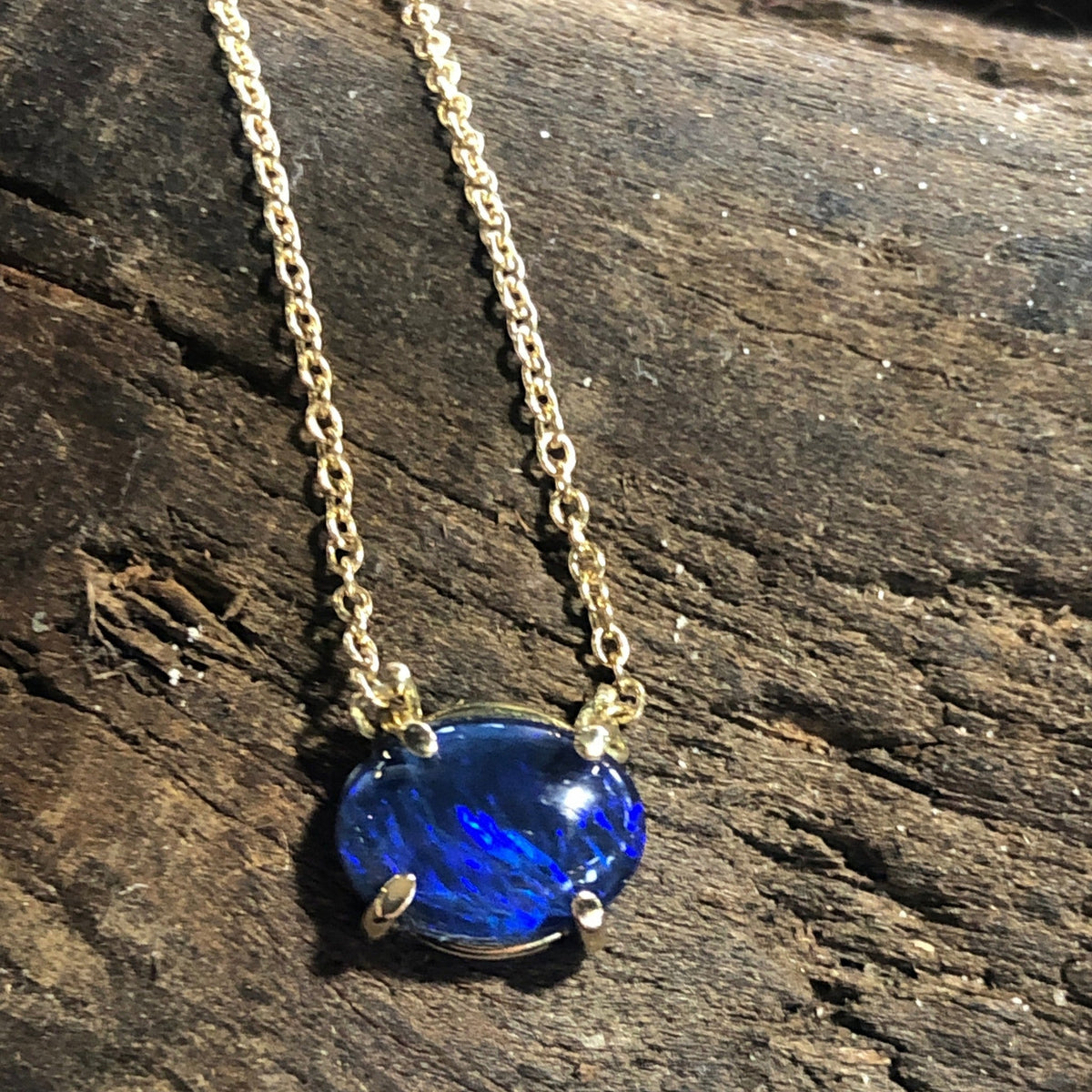 Collana MandalaT con opale blu intenso incastonato in oro su base di legno rustico