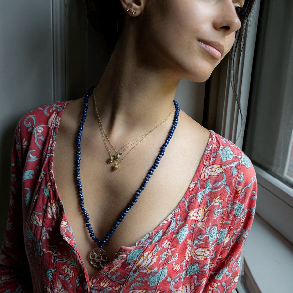 Collana MandalaT con radice di loto in argento e perline blu indossata da una donna con abito floreale