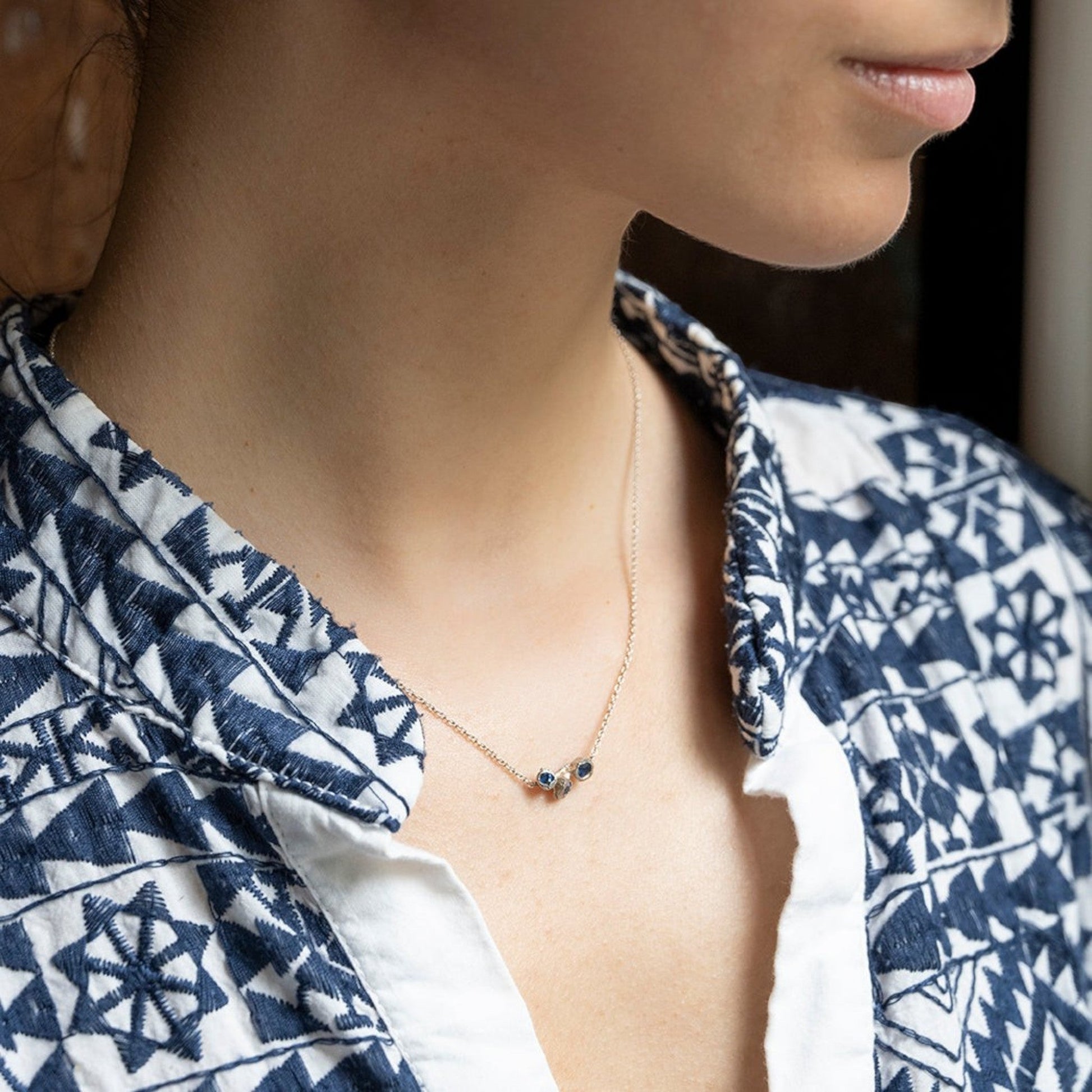 Collana MandalaT Callistemone in argento con tre pietre blu incastonate, indossata su una camicia a motivi geometrici