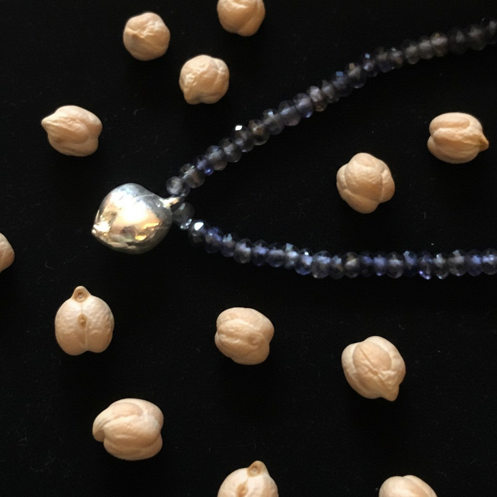Collana Cecio di MandalaT con ciondolo a forma di cece in argento e catenina di perline scure su sfondo nero