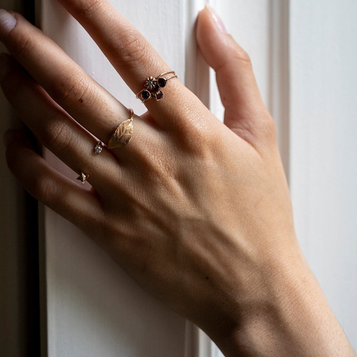 Anello Alloro MandalaT in oro con design a foglia indossato su una mano femminile vicino a un altro anello floreale