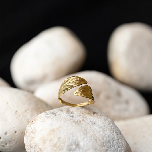 Anello aperto MandalaT modello Alloro in metallo dorato con texture a foglia poggiato su pietre bianche