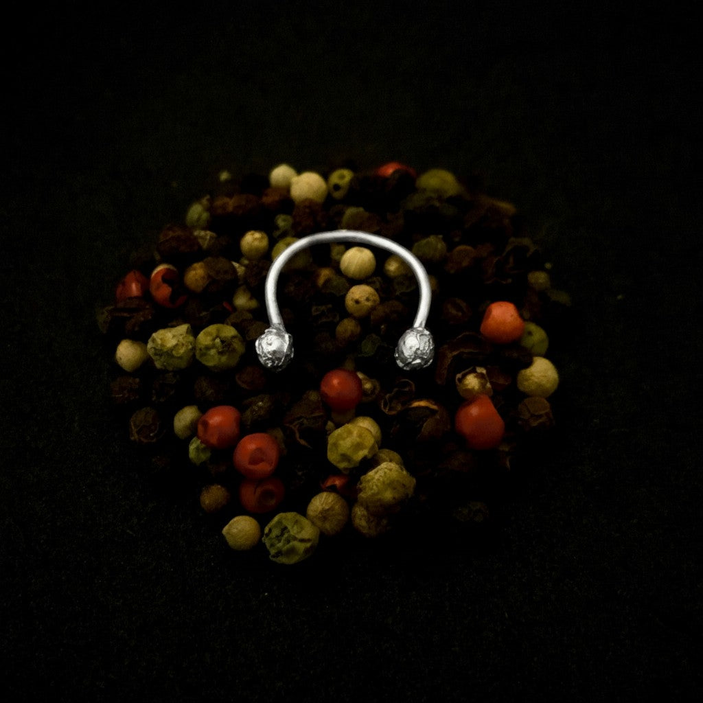 Anello aperto MandalaT in argento con terminali a forma di chicchi di pepe su un letto di grani di pepe misti