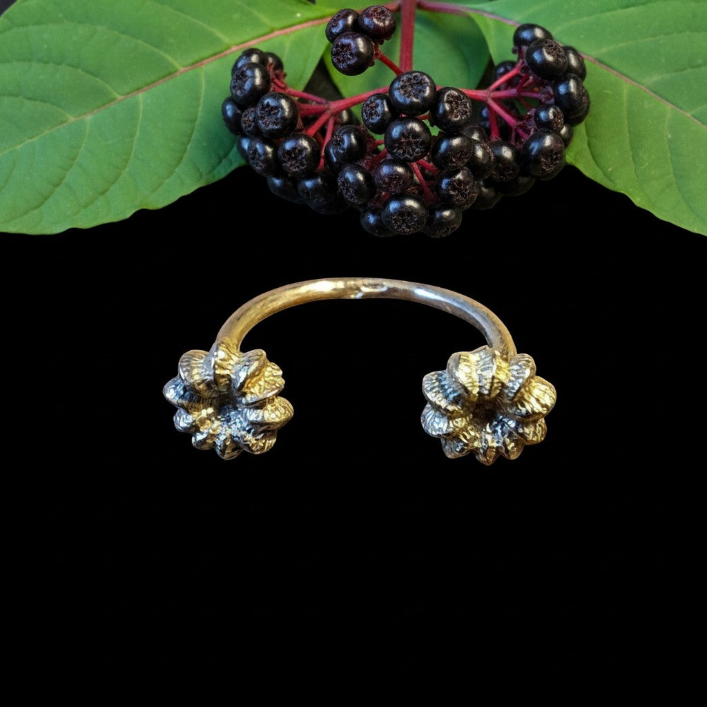 Anello aperto MandalaT in metallo dorato con dettagli floreali ispirati alla Phytolacca su sfondo nero
