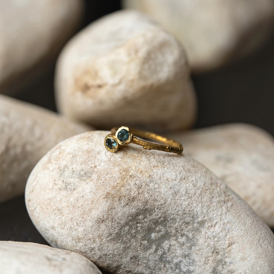 Anello MandalaT Callistemone a forma di ramo in oro con due pietre preziose blu incastonate su una pietra naturale