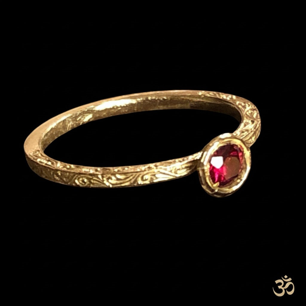 Anello MandalaT Amartya in oro con incisioni floreali e granato incastonato su sfondo nero