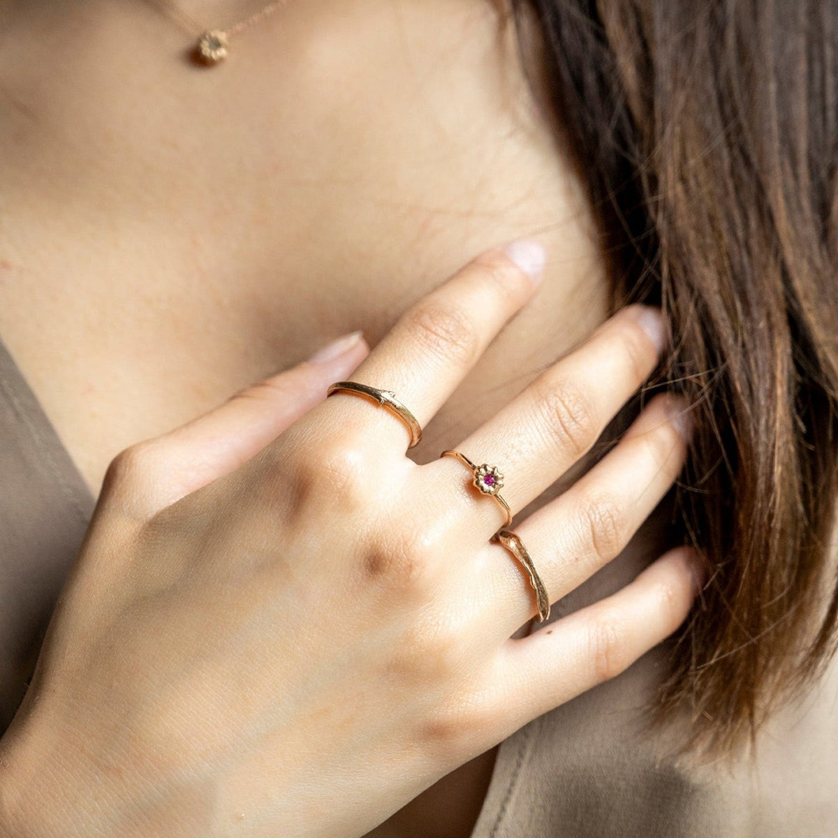 Anello MandalaT Phytolacca in oro rosa con piccolo rubino indossato su una mano femminile