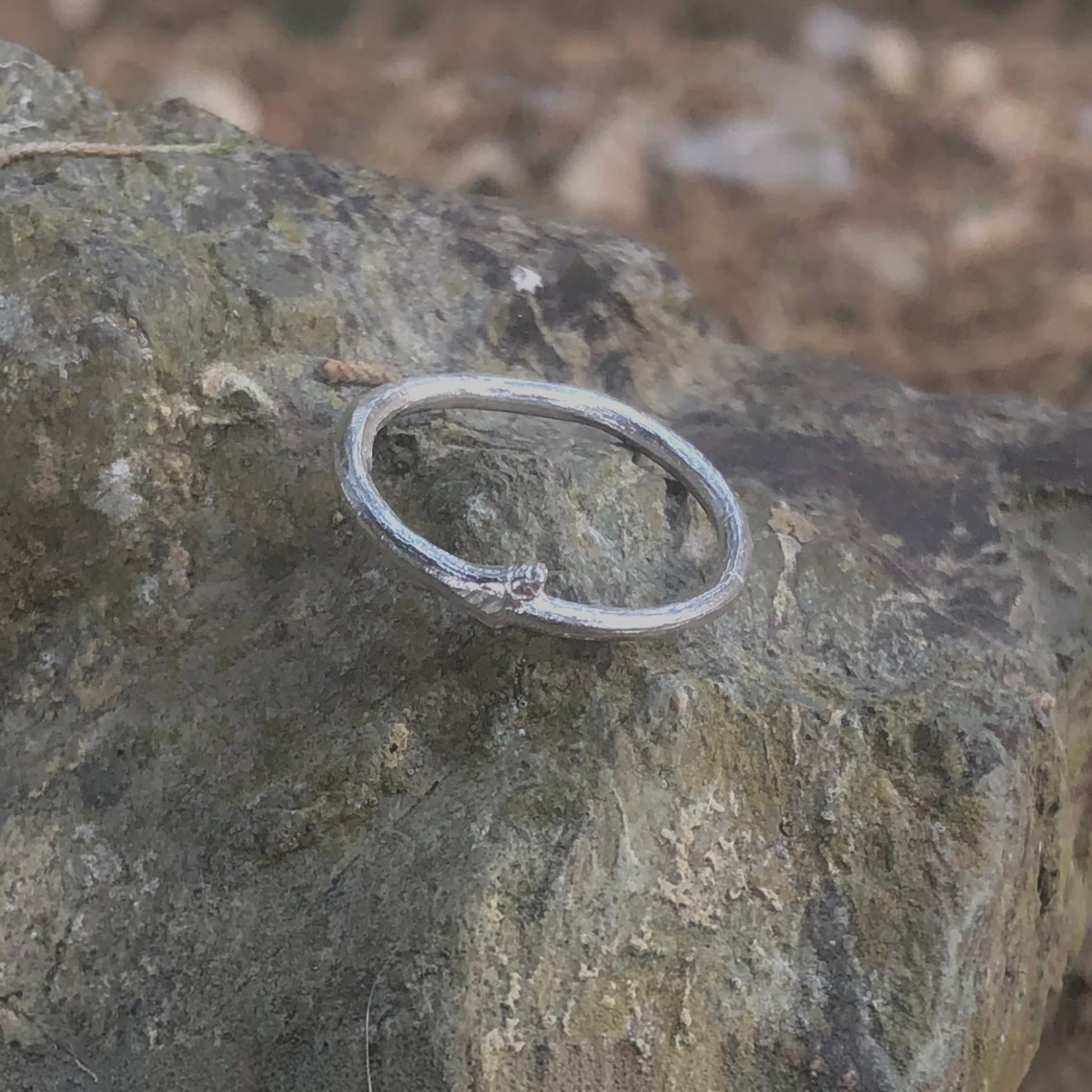 Anello MandalaT a forma di ramo in argento con texture naturale, poggiato su una roccia ruvida.