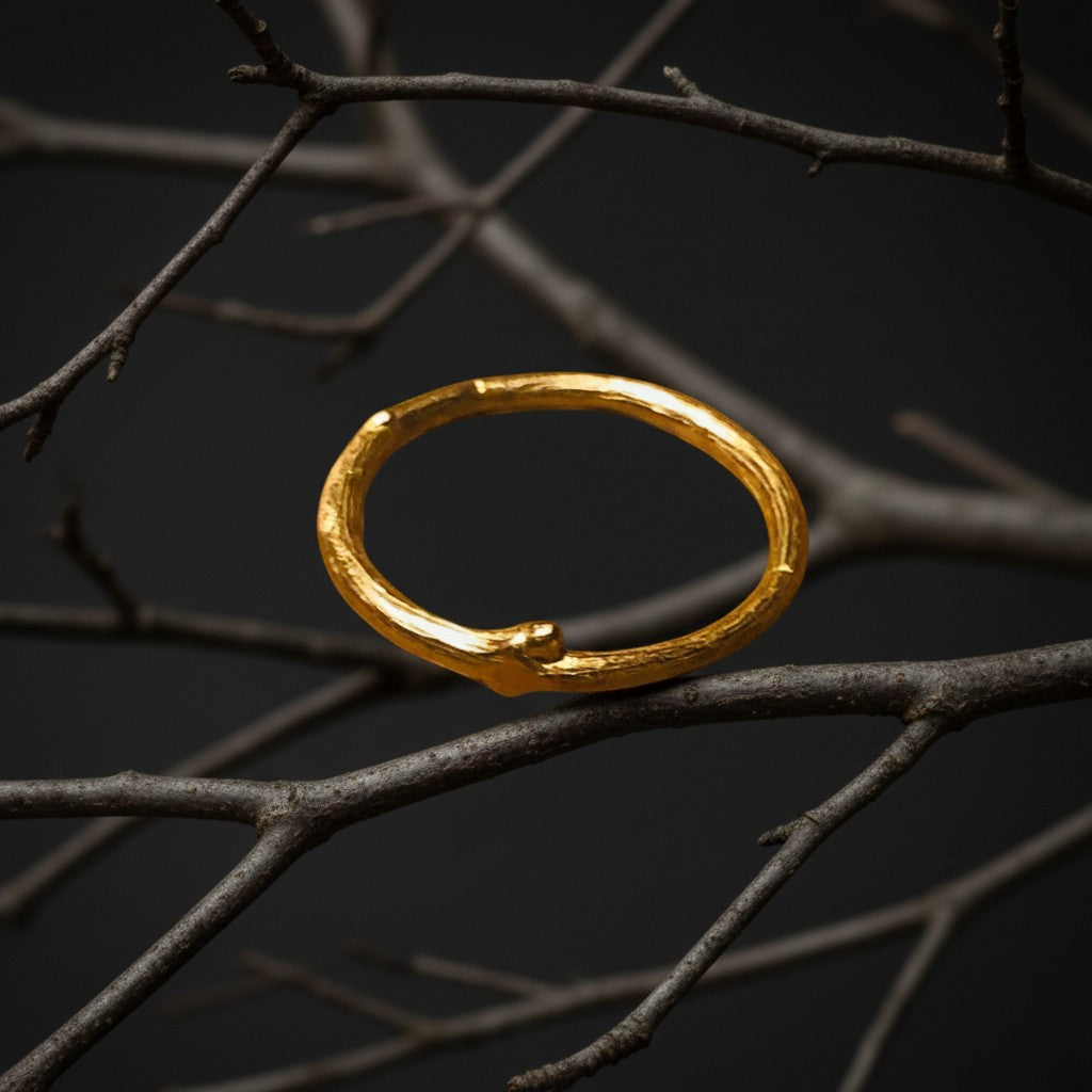 Anello MandalaT a forma di ramo dorato con texture naturale, poggiato su un rametto scuro