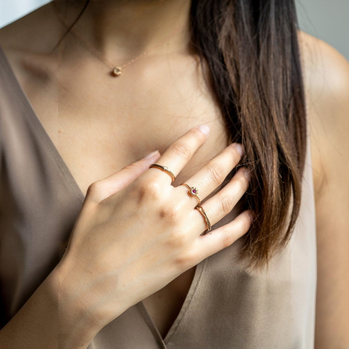 Anello MandalaT a forma di ramo in oro con piccola pietra rossa indossato su una mano femminile