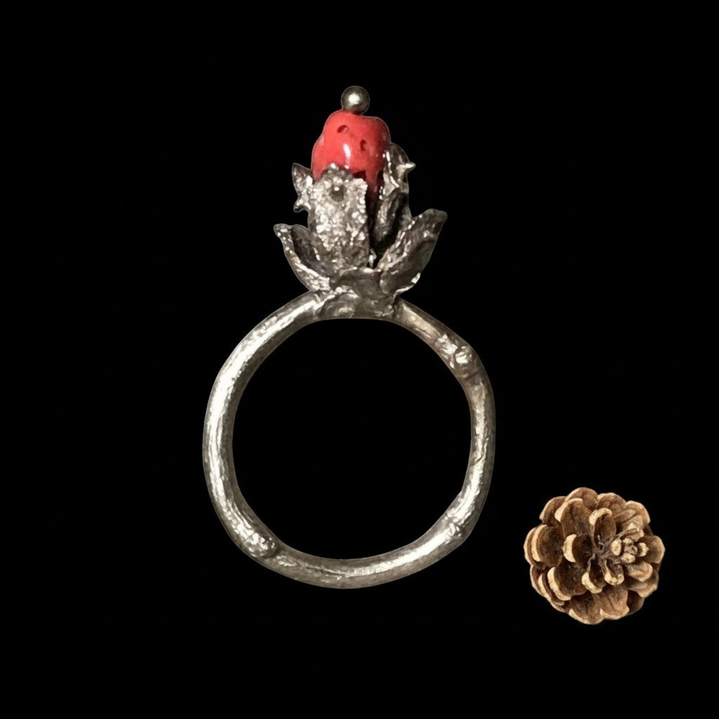 Anello MandalaT Tuia in metallo con texture organica e corallo rosso naturale a forma di pigna su sfondo nero