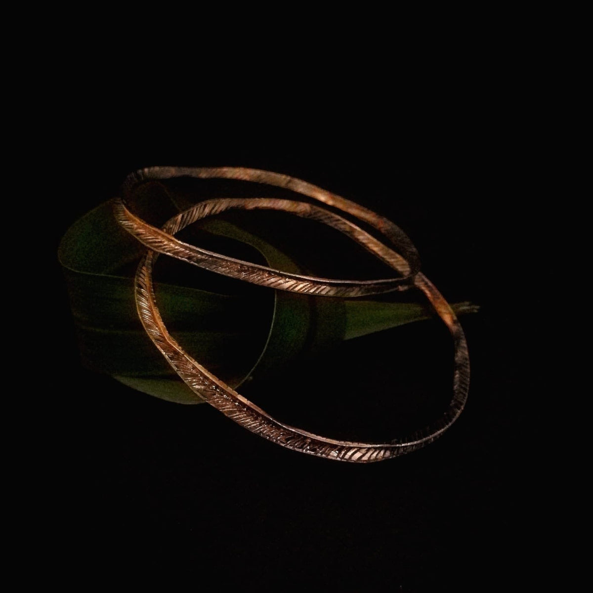 Bracciale Filo d’erba MandalaT in bronzo rosso con texture incisa ispirata a un filo d'erba su sfondo nero