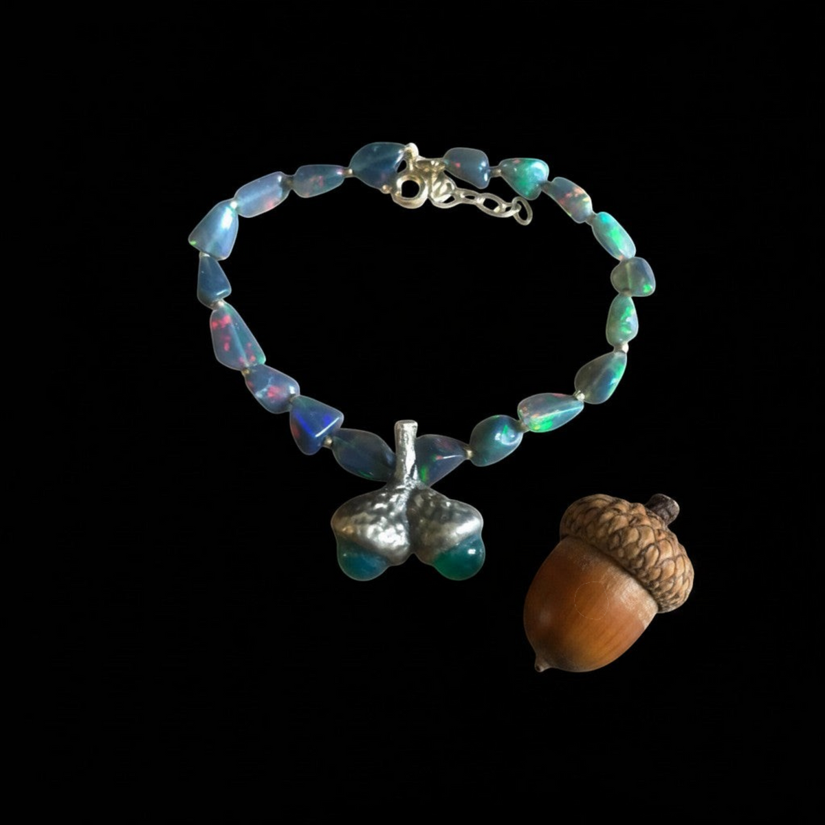 Bracciale MandalaT con ghiande in bronzo e pietre di opale scuro dai riflessi cangianti su sfondo nero