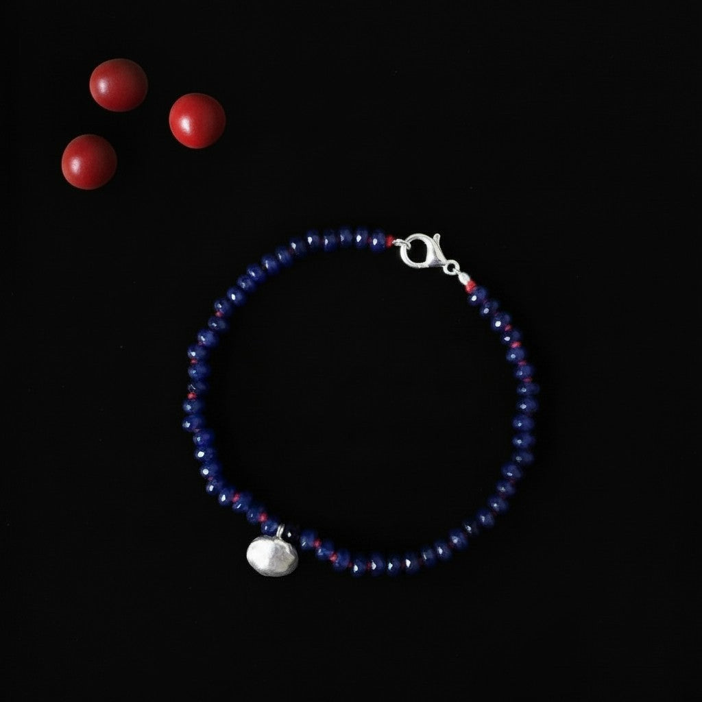 Bracciale MandalaT Ratan Gunja con perle di vetro blu, dettagli in argento e semi rossi su sfondo nero