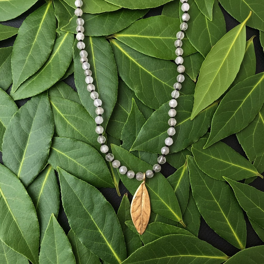Collana MandalaT con Labradorite annodata e ciondolo a forma di foglia d'alloro in bronzo su letto di foglie verdi