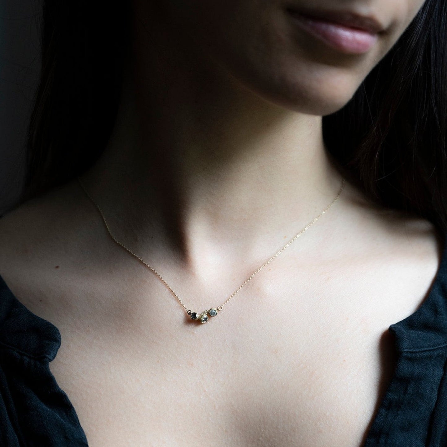 Collana MandalaT Callistemone in oro con tre pietre incastonate ispirate ai fiori, indossata su una modella.