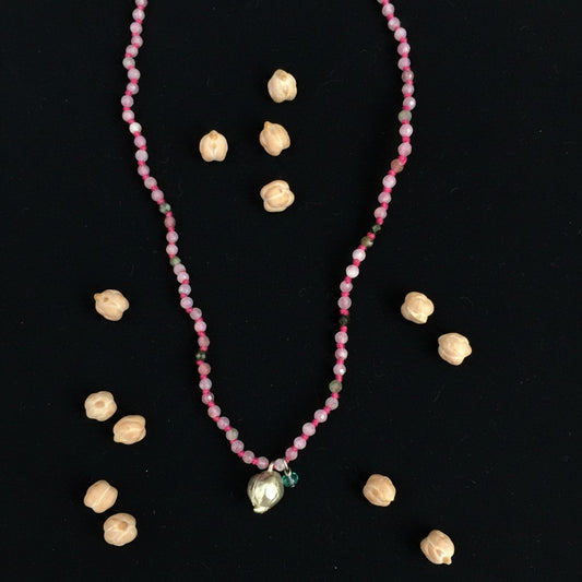 Collana MandalaT Cecio con perline rosa sfaccettate e ciondolo a forma di cece su sfondo nero con ceci veri