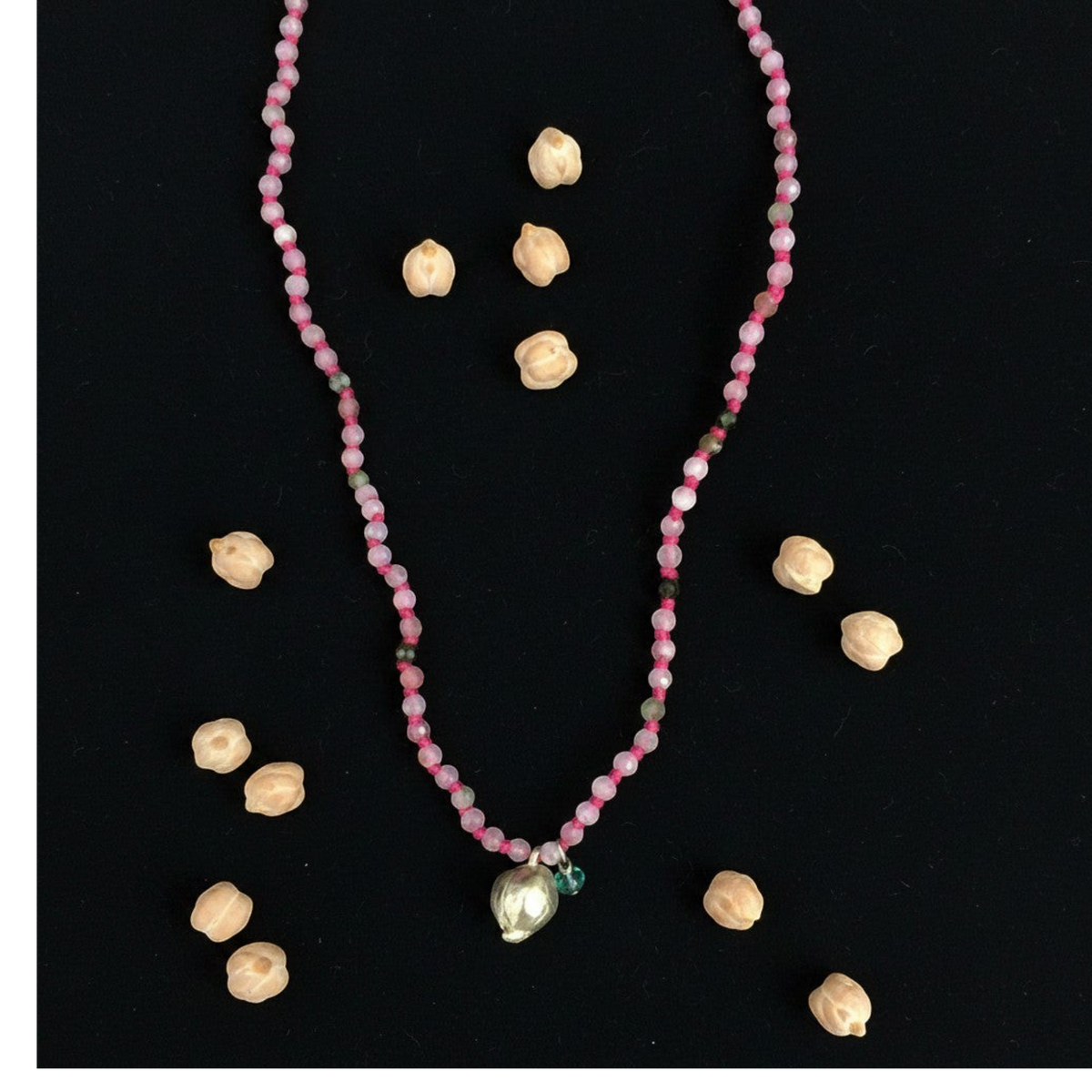 Collana MandalaT Cecio con perline rosa sfaccettate e ciondolo a forma di cece su sfondo nero con ceci veri