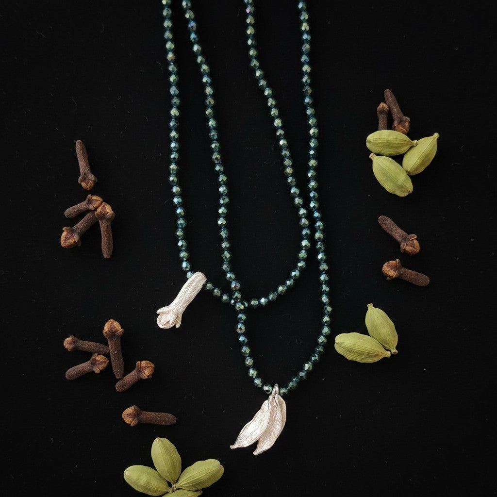 Collana MandalaT con perline verdi sfaccettate e ciondoli a forma di chiodo di garofano in argento su sfondo nero