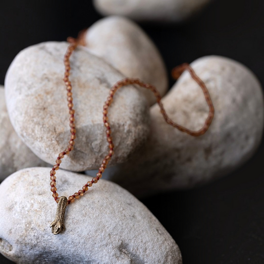 Collana MandalaT con ciondolo a forma di chiodo di garofano in oro su catenina di perline color ambra su pietre