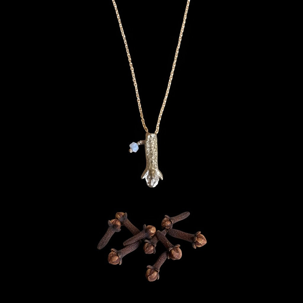 Collana MandalaT in oro con ciondolo a forma di chiodo di garofano e piccola pietra azzurra su sfondo nero