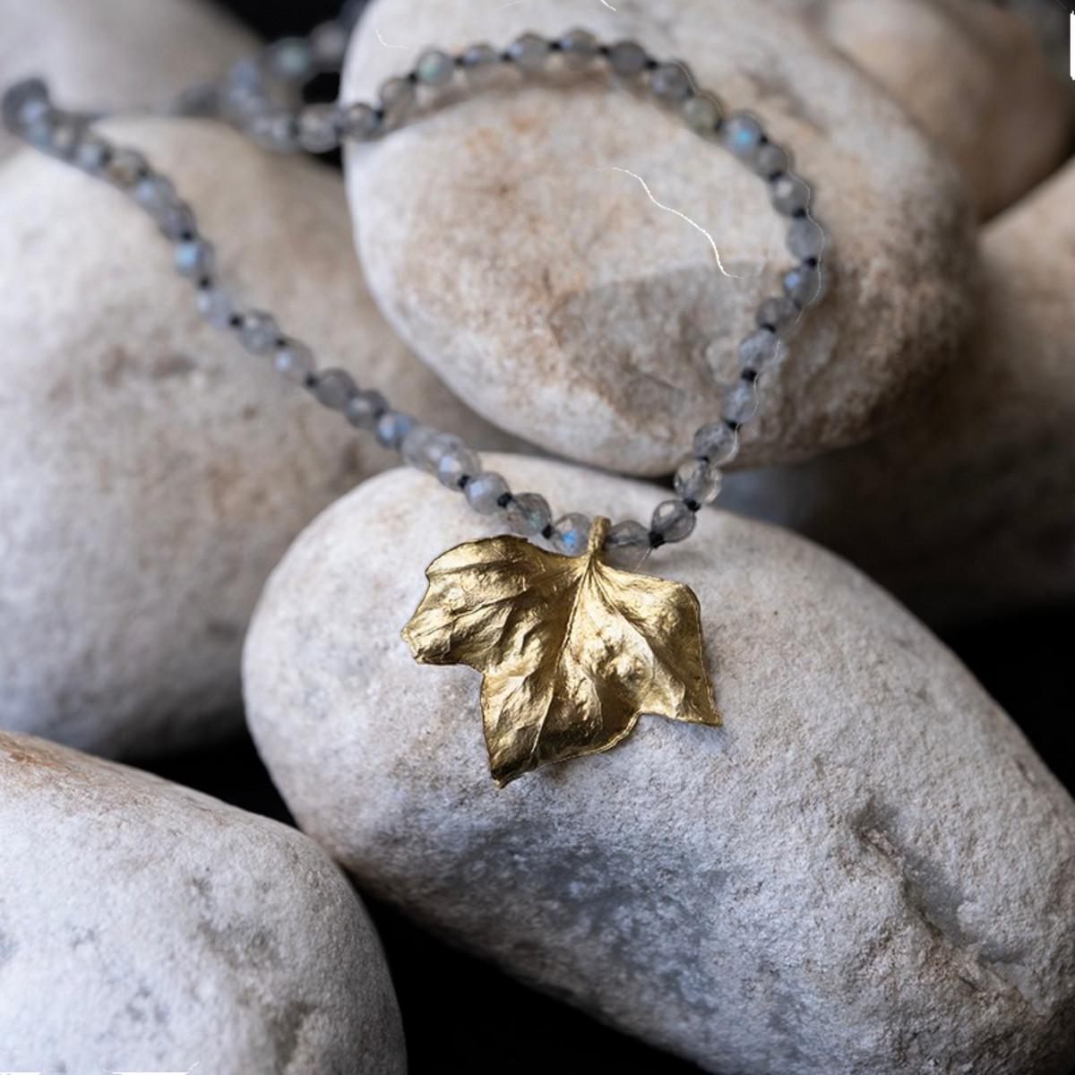 Collana Edera MandalaT con ciondolo a foglia in bronzo dorato e catenina di pietre naturali grigie su sassi bianchi