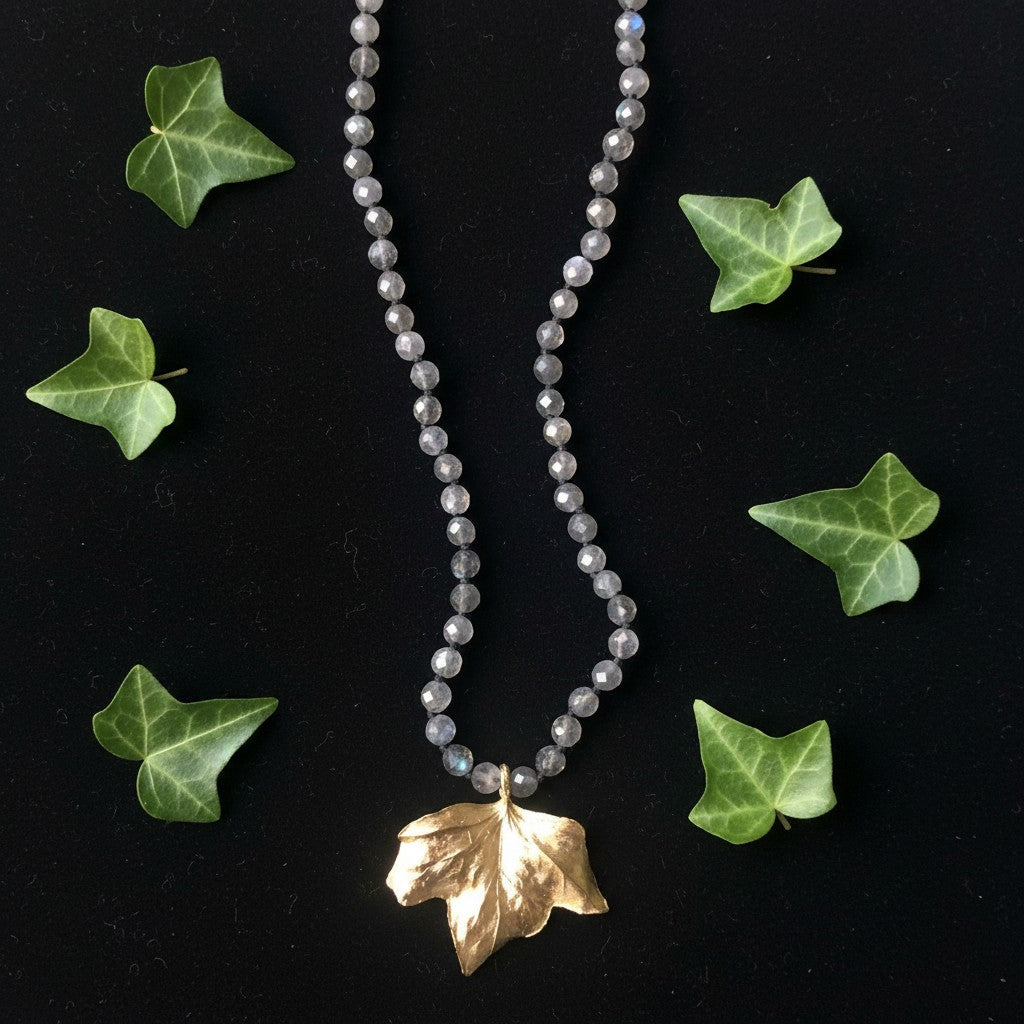 Collana Edera MandalaT con ciondolo a foglia dorata e catena di labradorite sfaccettate con nodi neri su sfondo nero