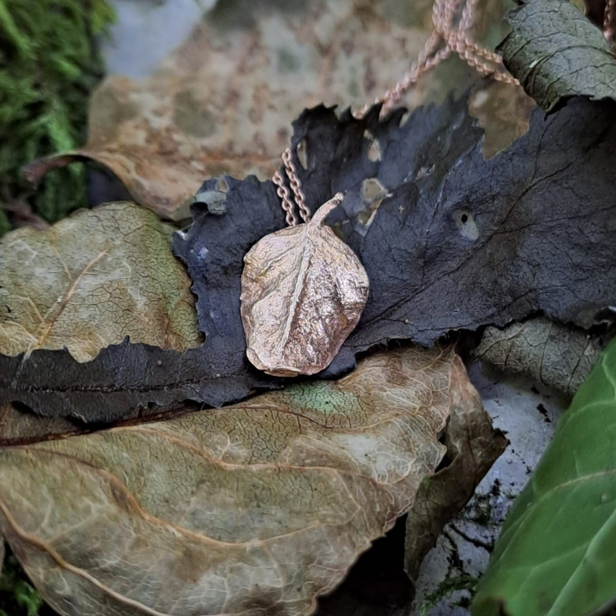 Collana MandalaT con ciondolo a forma di foglia di cappero in oro rosa su foglie secche naturali