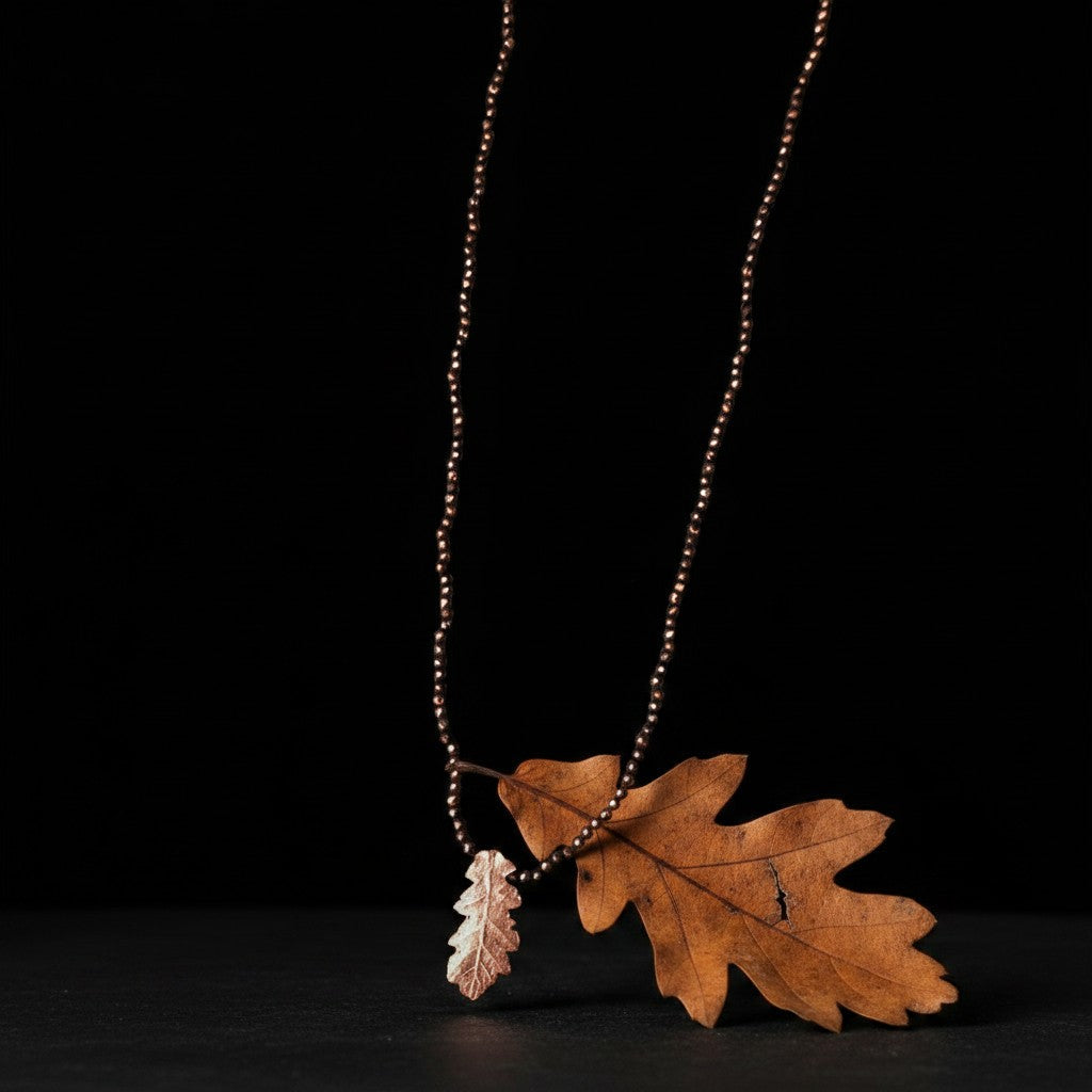 Collana MandalaT con ciondolo a forma di foglia di quercia in oro rosa con Ematite su sfondo nero con foglia secca naturale