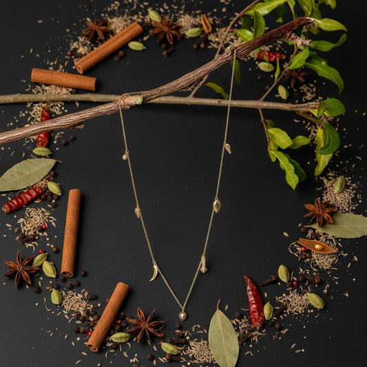 Collana MandalaT Masala in oro con ciondoli a forma di semi e spezie su sfondo nero decorato con spezie naturali