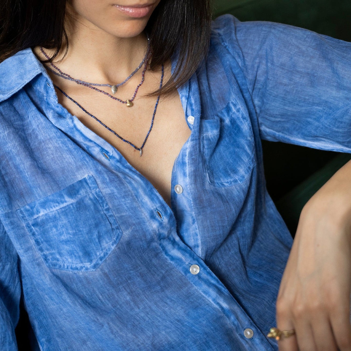 Collana MandalaT con ciondolo melograno e radici di rubino indossata da una donna con camicia azzurra