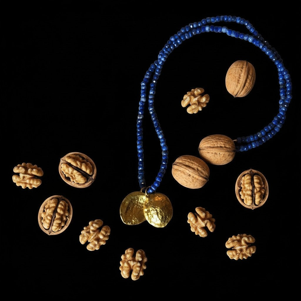 Collana MandalaT Noce con pendente dorato e catena di perline blu, circondata da noci su sfondo nero.