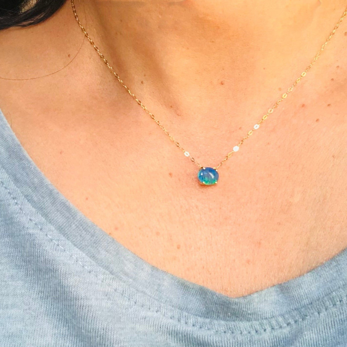 Collana MandalaT con ciondolo in opale blu rotondo montato su una sottile catenina d'oro indossata al collo
