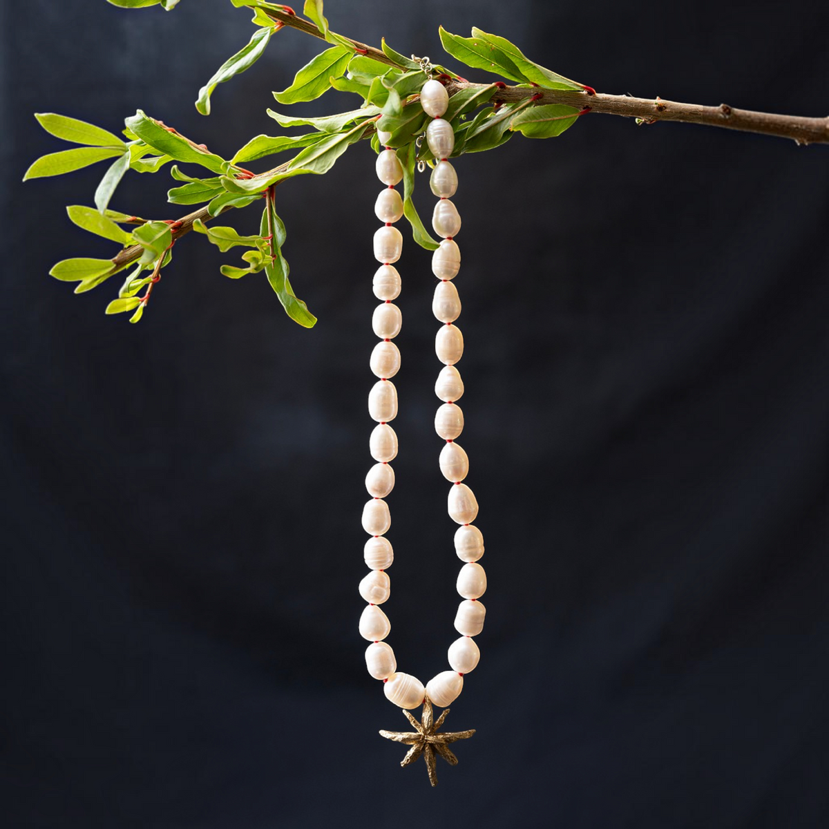 Collana MandalaT con perle naturali bianche e ciondolo artigianale a forma di anice stellato su ramo verde