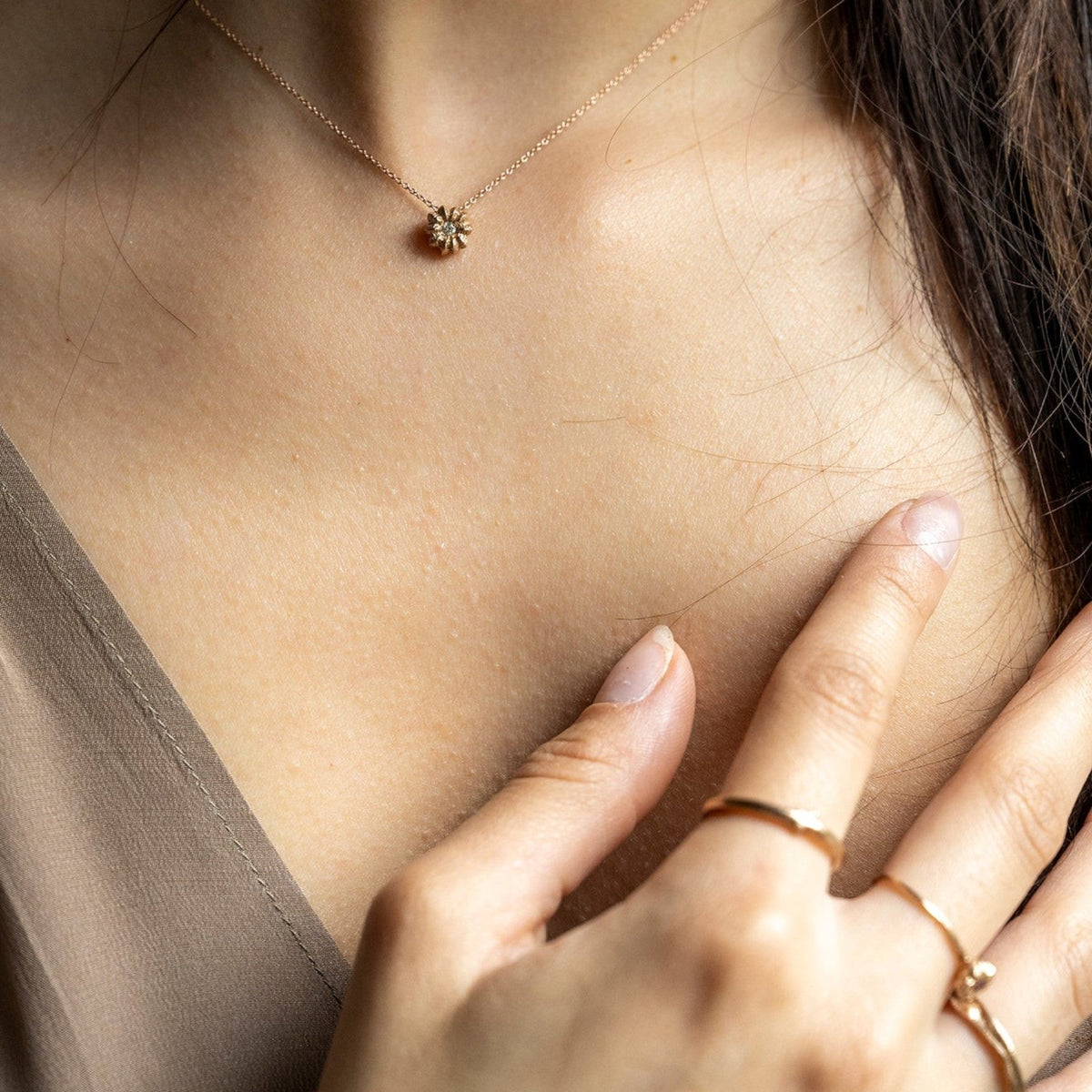 Collana MandalaT Phytolacca in oro con pendente a forma di fiore indossata da una donna