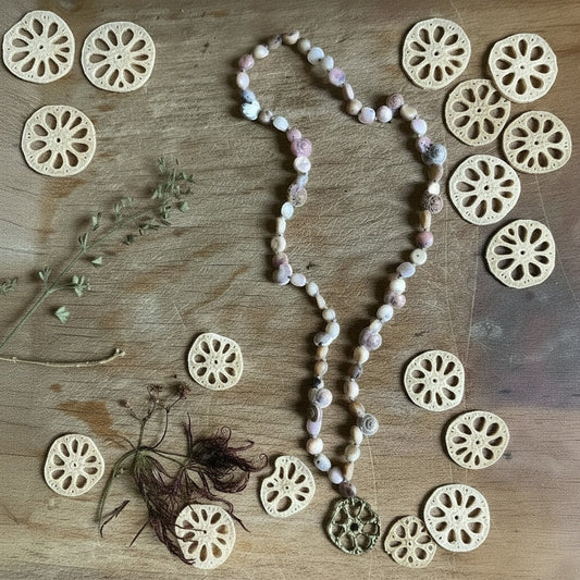 Collana MandalaT con ciondolo radice di loto in metallo e catena di pietre dure naturali su sfondo in legno