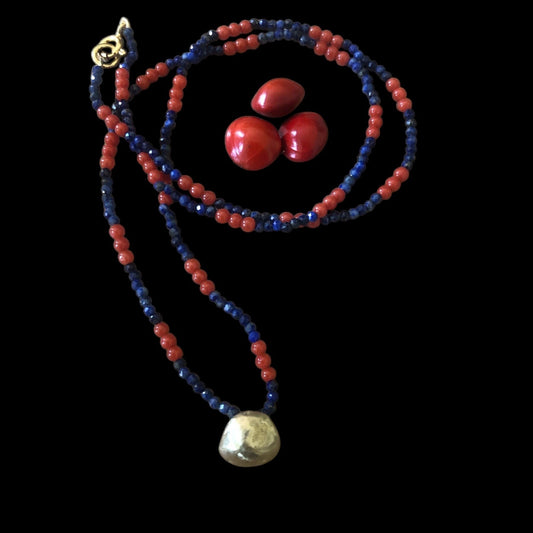Collana MandalaT con semi Ratan gunj rossi al centro, perline di lapislazzuli alternato con perline di corallo autentico e ciondolo di fusione di ratan gunj in bronzo su sfondo nero