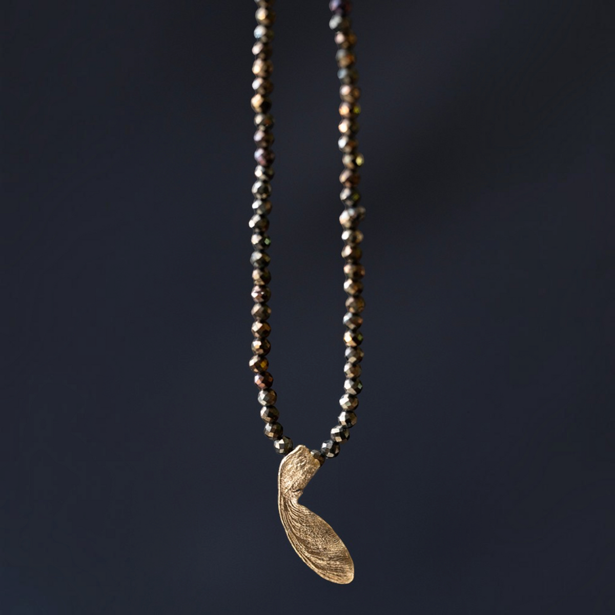 Collana MandalaT con ciondolo a forma di seme di acero dorato e catenina di perline scure sfaccettate