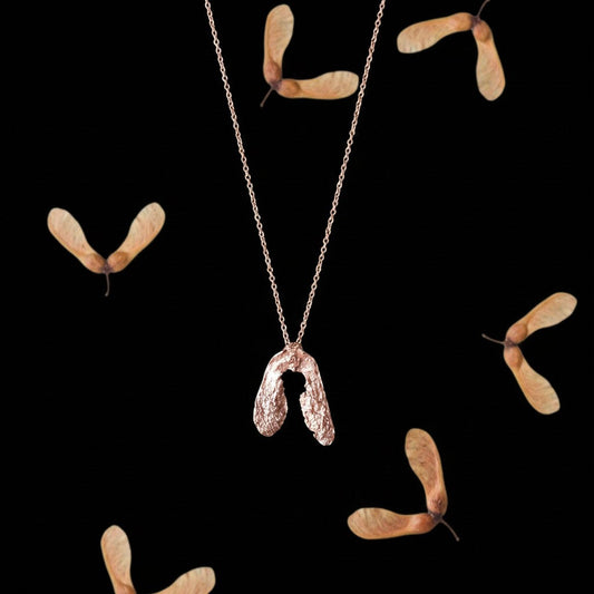 Collana MandalaT a forma di seme di acero in oro rosa con catenina sottile su sfondo nero