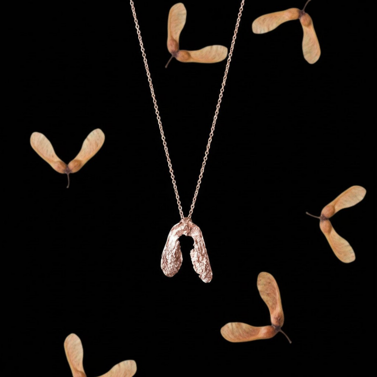 Collana MandalaT a forma di seme di acero in oro rosa con catenina sottile su sfondo nero