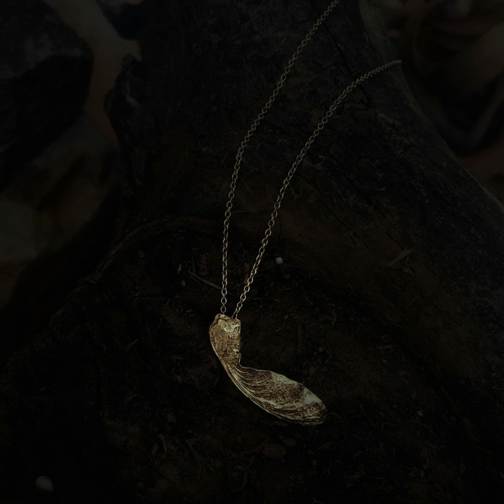 Collana MandalaT con ciondolo a forma di seme di acero in oro su base di legno scuro