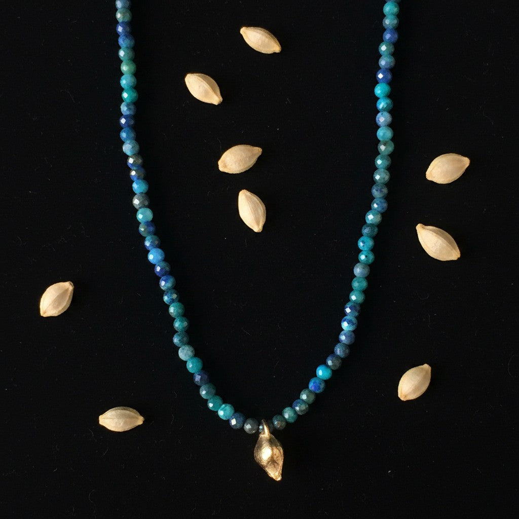 Collana MandalaT con perline sfaccettate di Turchese e ciondolo dorato a forma di seme di limone su sfondo nero