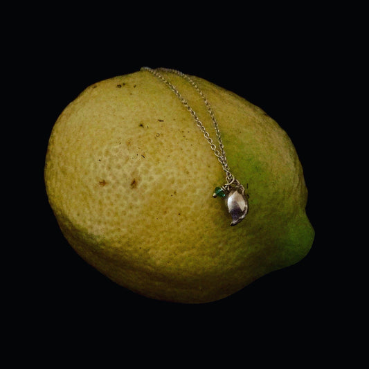 Collana MandalaT in argento con ciondolo a forma di seme di limone e piccolo smeraldo su sfondo nero