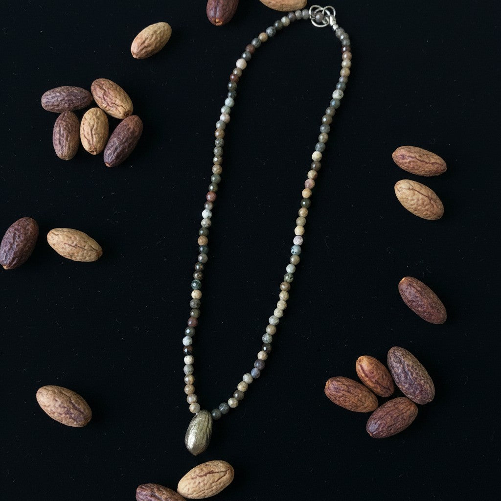 Collana MandalaT con perline sfaccettate nei toni della terra e ciondolo a forma di seme di ulivo su sfondo nero