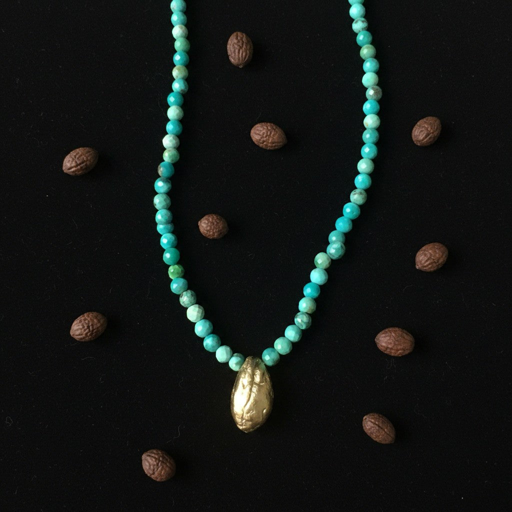 Collana MandalaT con perline di  turchese e ciondolo a forma di seme d'ulivo dorato su sfondo nero