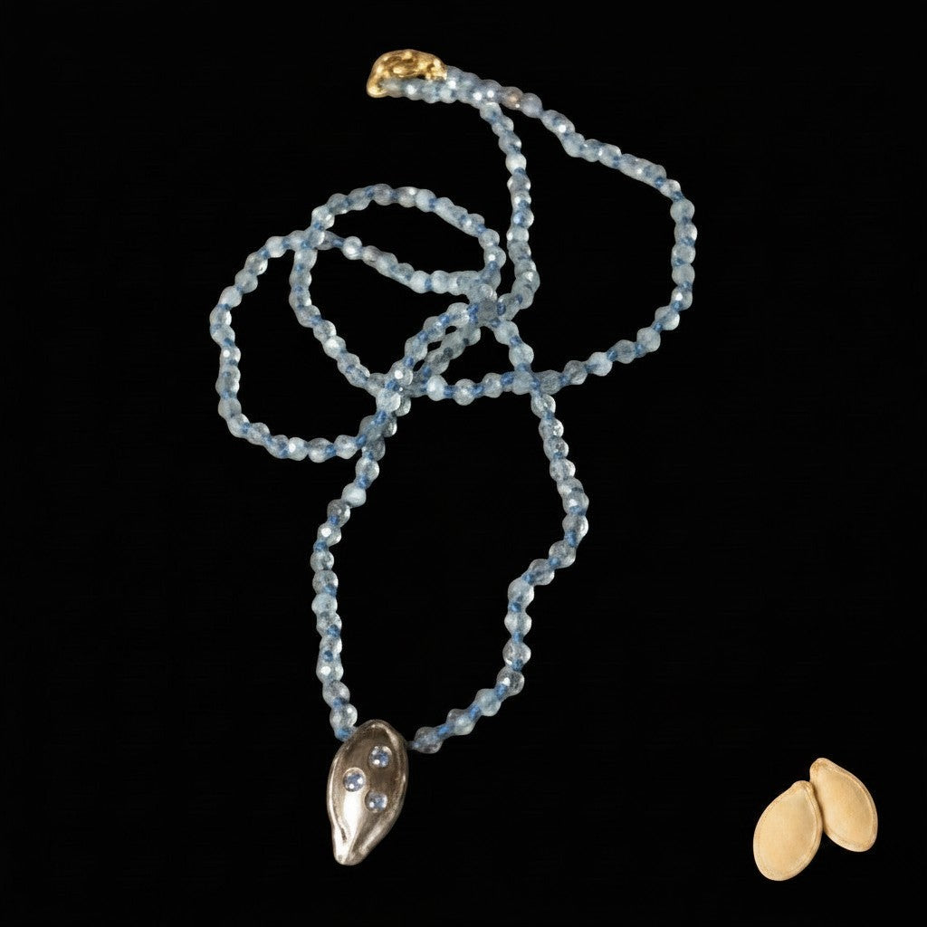 Collana MandalaT con ciondolo seme di zucca in metallo e pietre azzurre su catena di perline sfaccettate