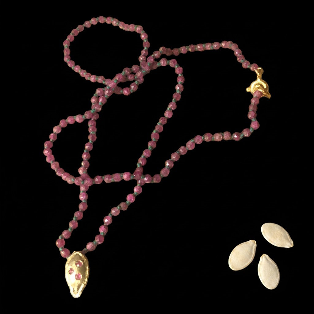Collana MandalaT con pietre sfaccettate di radice di rubino e ciondolo a forma di seme di zucca in oro con tre rubini