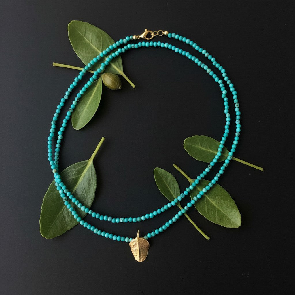 Collana MandalaT con turchesi e ciondolo a forma di foglia di cappero in bronzo su sfondo nero